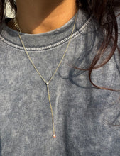 Load image into Gallery viewer, Willow Roe 14K gold Eden single diamond lariat necklace worn on a model with a blue shirt. 
