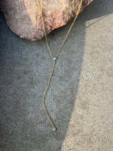 Load image into Gallery viewer, Willow Roe 14k gold single diamond lariat necklace on gray background
